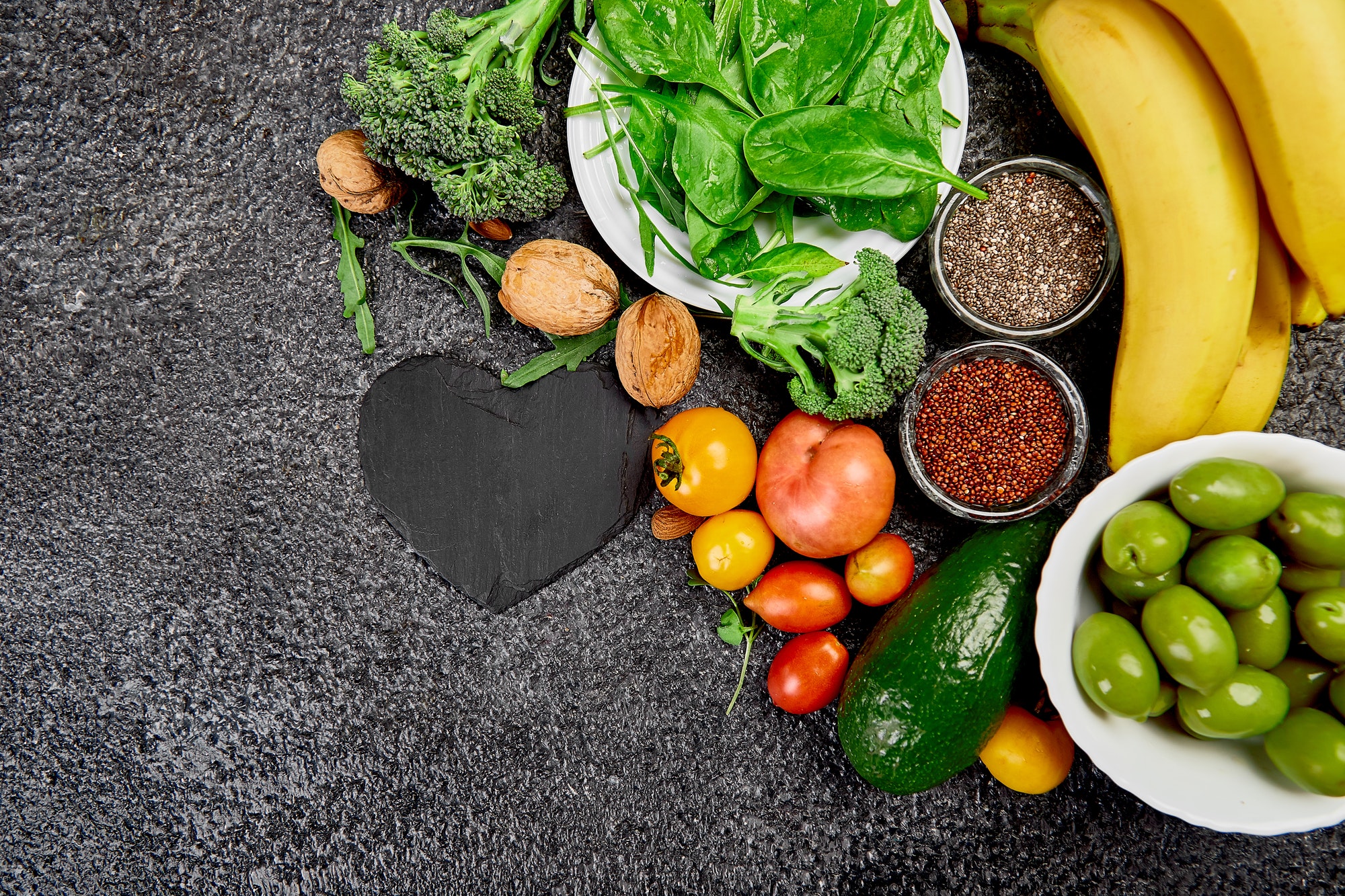 Fresh vegetables and whole foods arranged on a dark surface